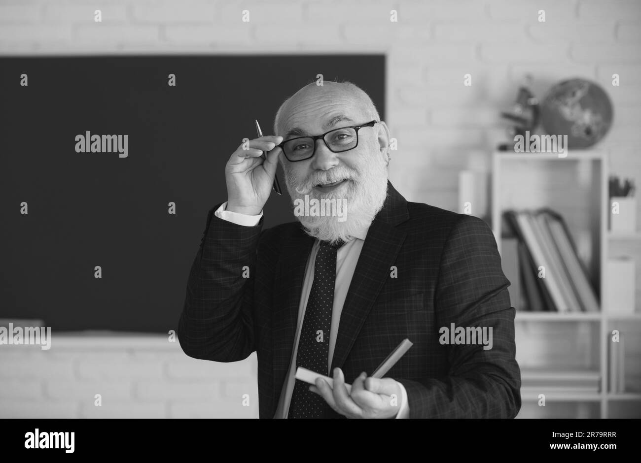 Elderly man teacher on a blank chalkboard during lesson, teaching class ...