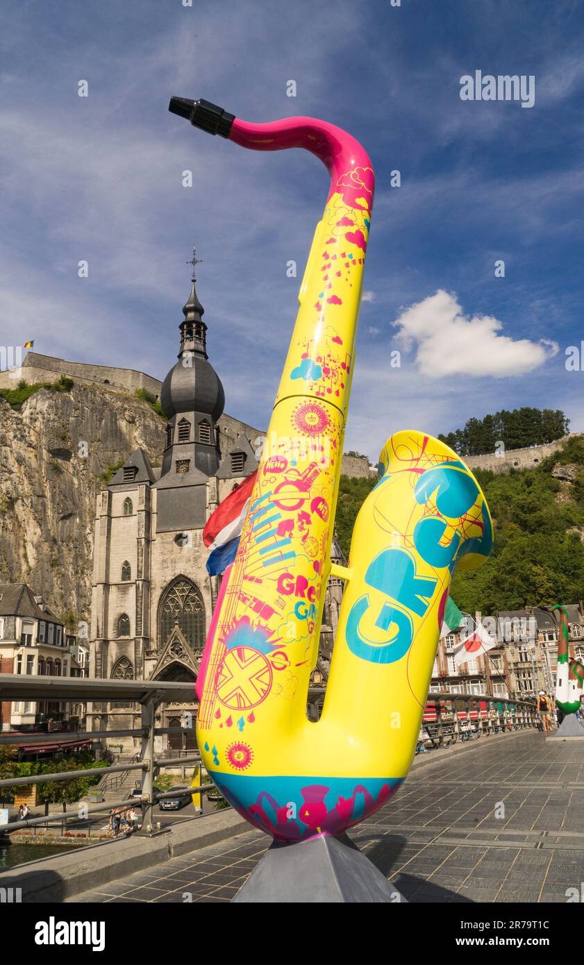 View of the Belgian town of Dinant, hometown of Adolphe Sax, inventor of the saxophone, with a saxophone in the foreground in vivid colors. Stock Photo