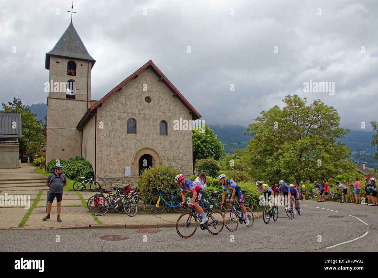 PINET, FRANCE, June 12, 2023 : Runners of the Criterium du Dauphine and the church of Pinet during last stage of this eight days cycling race. Stock Photo