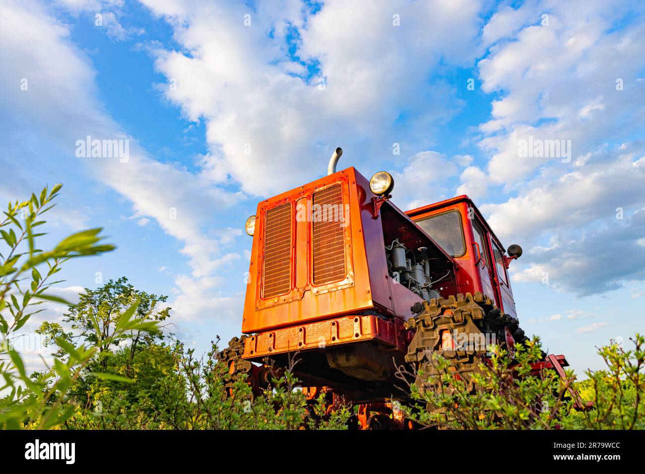 red tractor of the old model stands in the field. red old tractor. tractor photographed from a lower angle. old soviet tractor stands in the field Stock Photo