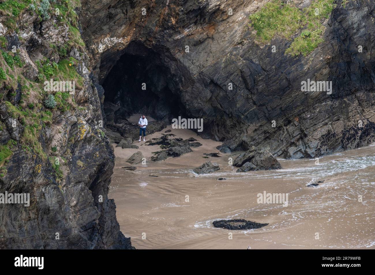 A holidaymaker visitor standing in a cave on Tolcarne Beach in Newquay in Cornwall in the UK. Stock Photo
