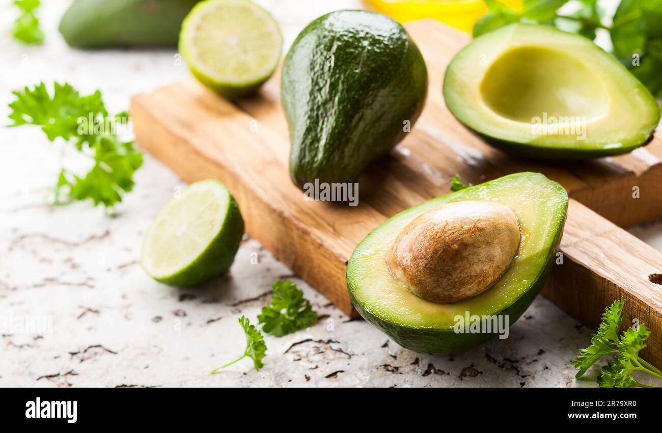 https://c8.alamy.com/comp/2R79XR0/a-whole-and-a-halved-avocado-on-wooden-board-2R79XR0.jpg