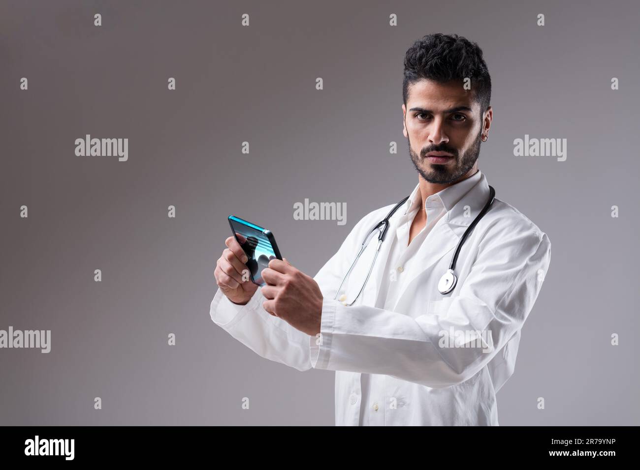 Doctor using digital tablet to analyze data and provide answers. This cool, slim, well-bearded medic with modern technology is just what you need Stock Photo