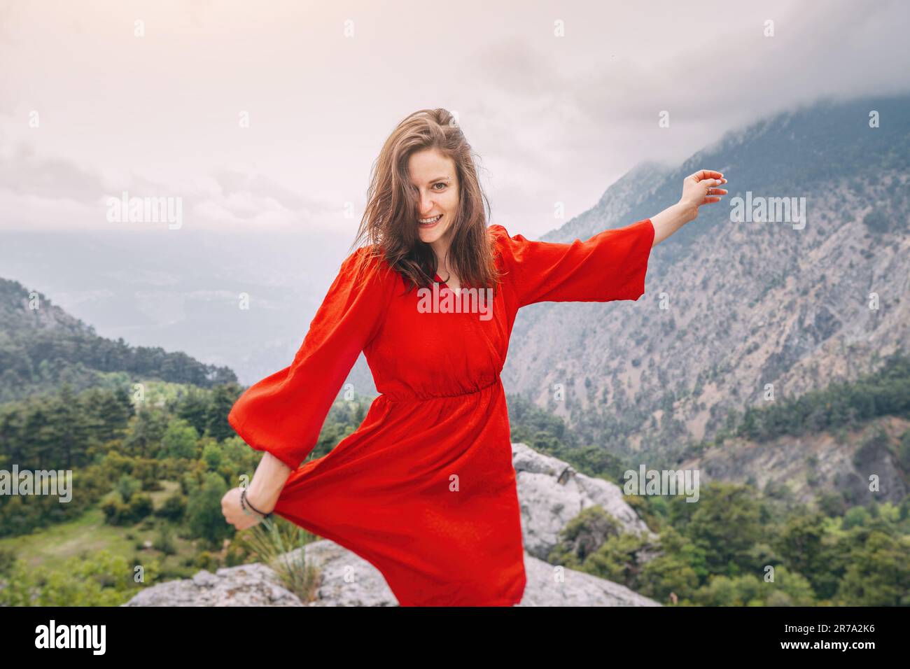 Romantic aerial photo of a girl in a red dress on top of a cliff ...