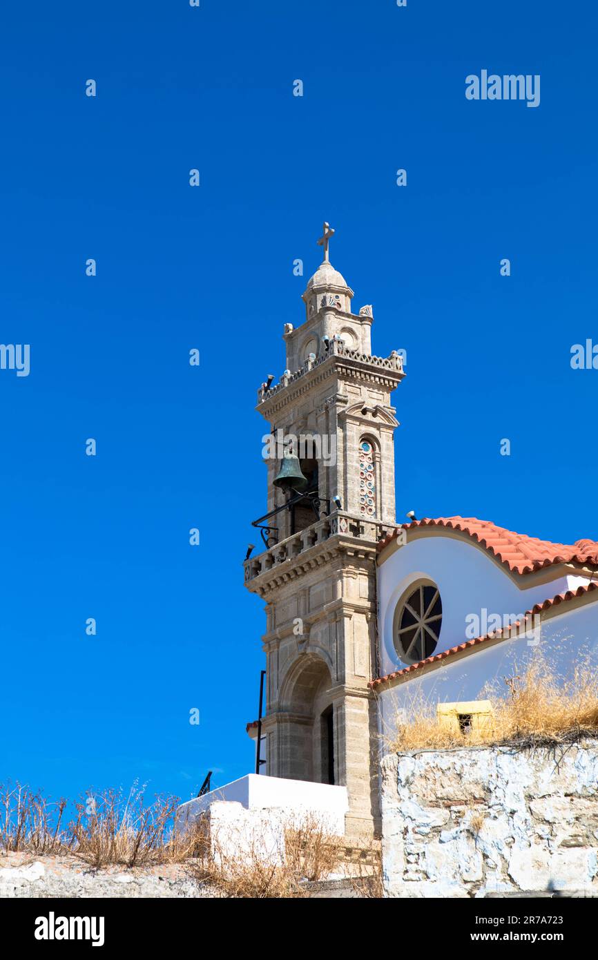 Church tower with bell against blue sky. Fanes, Rhodes island, Greece. Close up. Stock Photo