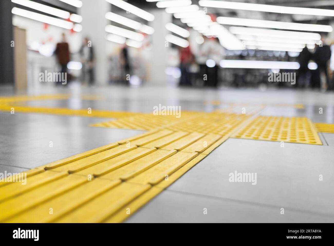 Yellow tactile tiles for the blind laid on a tiled floor in a store interior Stock Photo