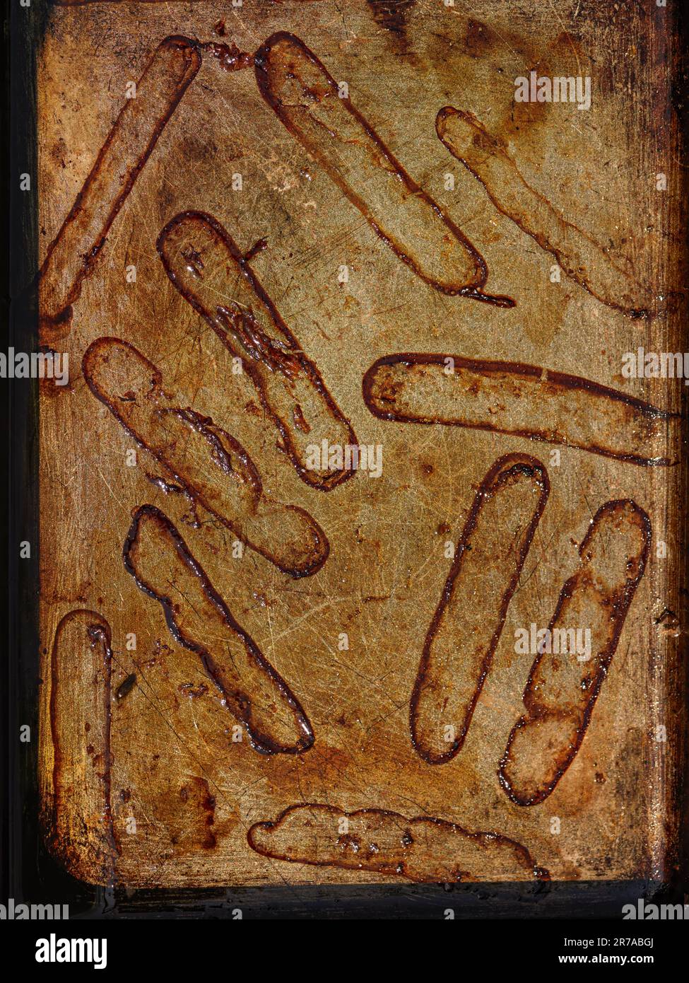 the outlines left by sausages after they have been cooked in an oven tray Stock Photo