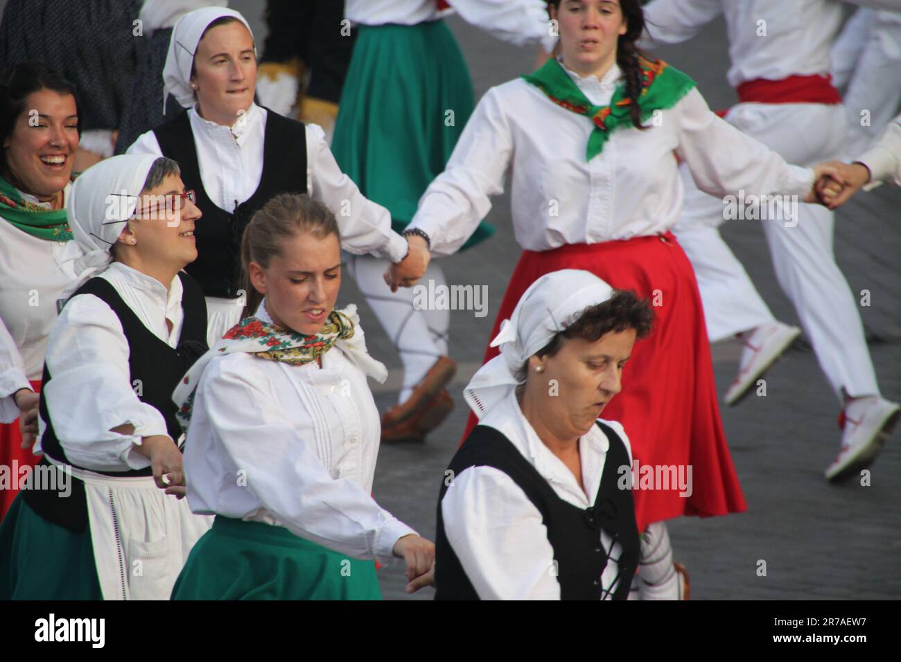 A group of female friends dressed in traditional period-style costumes are joyfully dancing in the street together Stock Photo