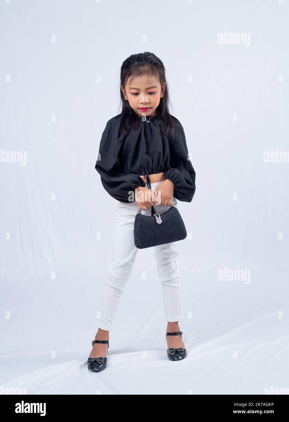 An Asian girl is dressed in a black and white outfit, featuring a long-sleeved top and matching skirt Stock Photo