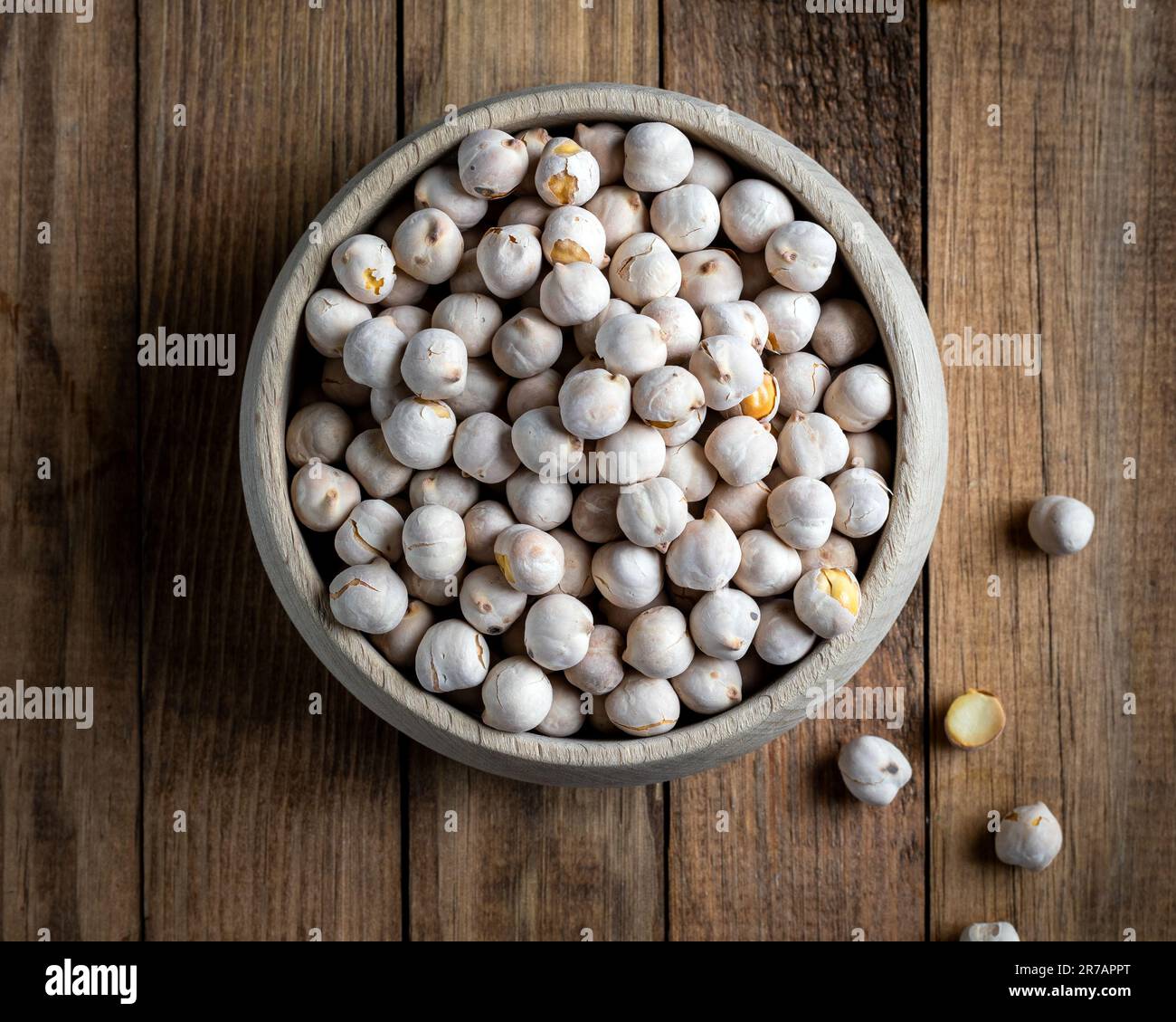Roasted white chickpeas in wooden bowl, traditional Turkish nut on wooden background. Turkish leblebi, famous nut, stack of yellow white roasted chick Stock Photo