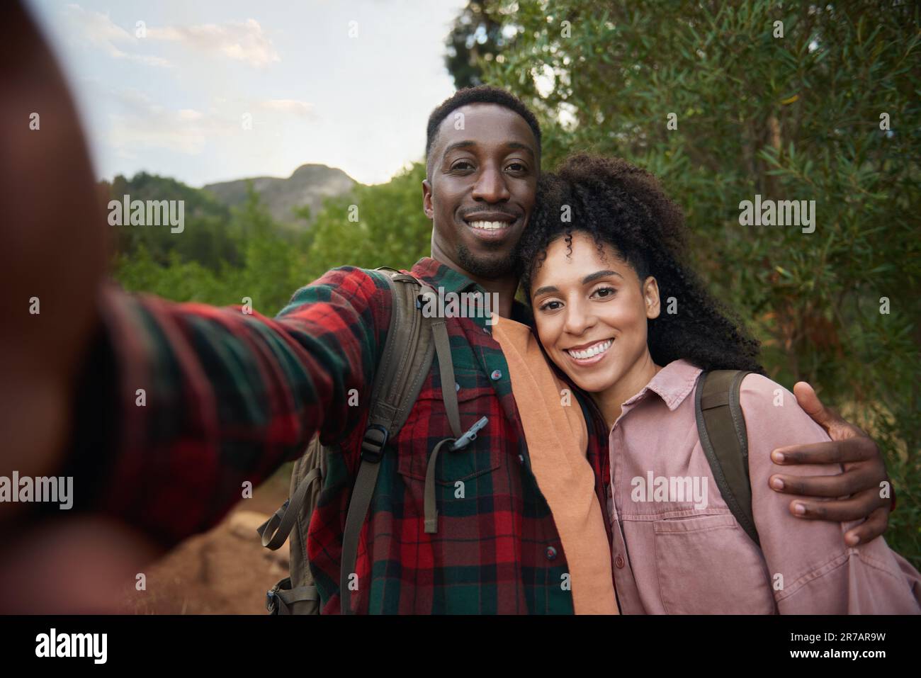 Smiling young multiethnic couple taking selfies on a hiking trail Stock Photo
