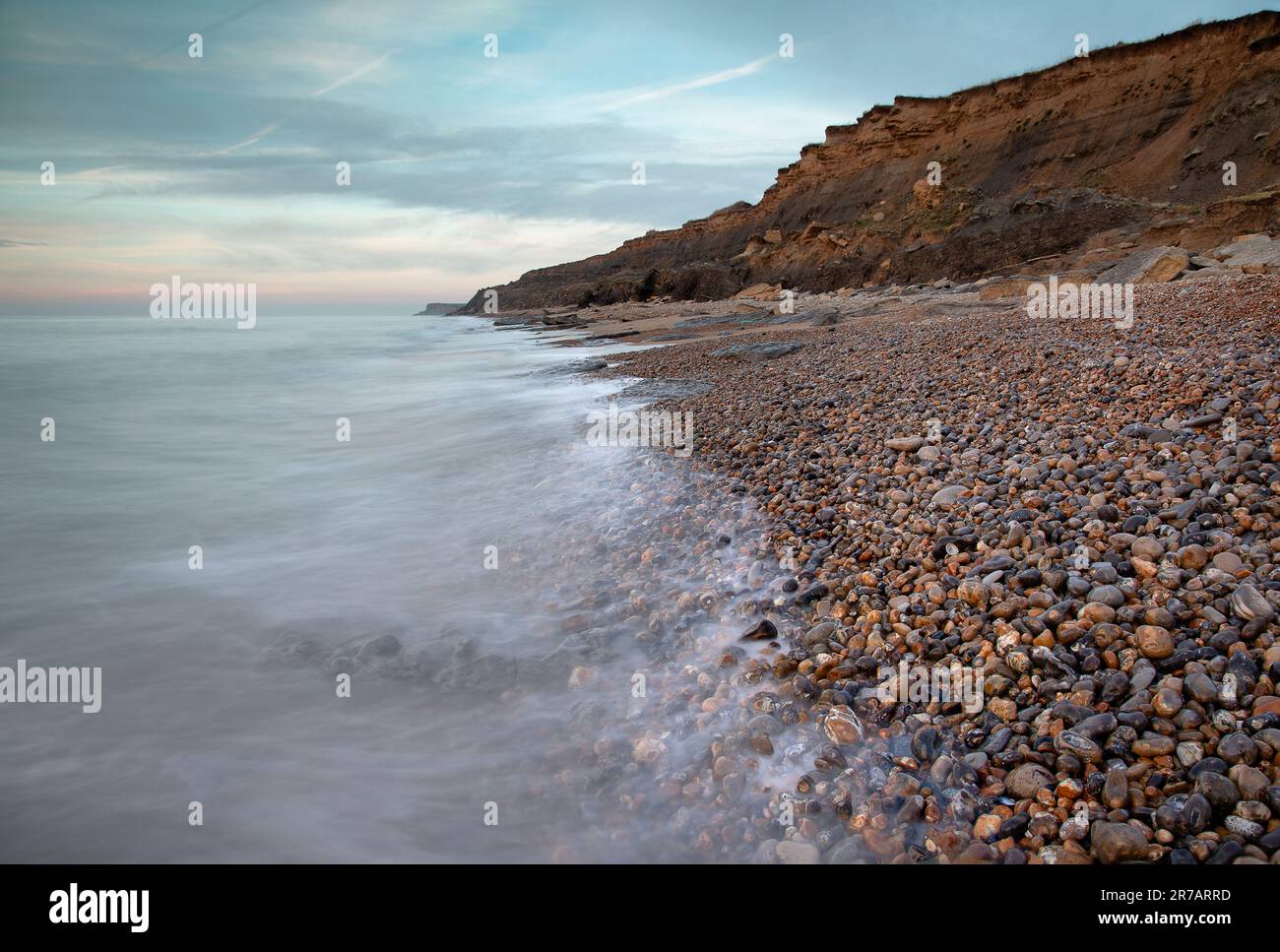 A landscape of the sea with long exposure surrounded by cliffs under a ...