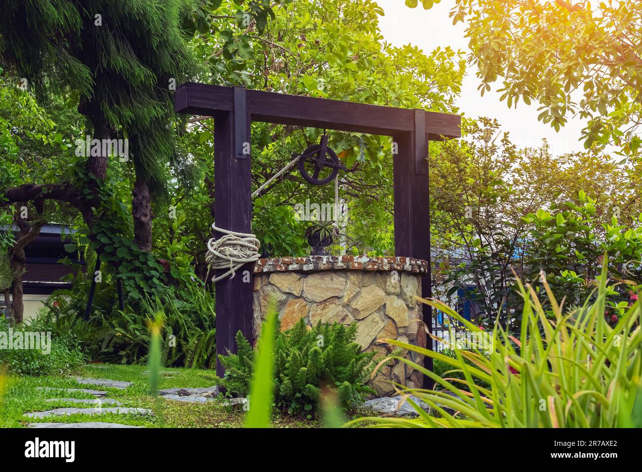 Beautiful artesian well made by stones and wheel pulley with metal bucket and rope in peaceful