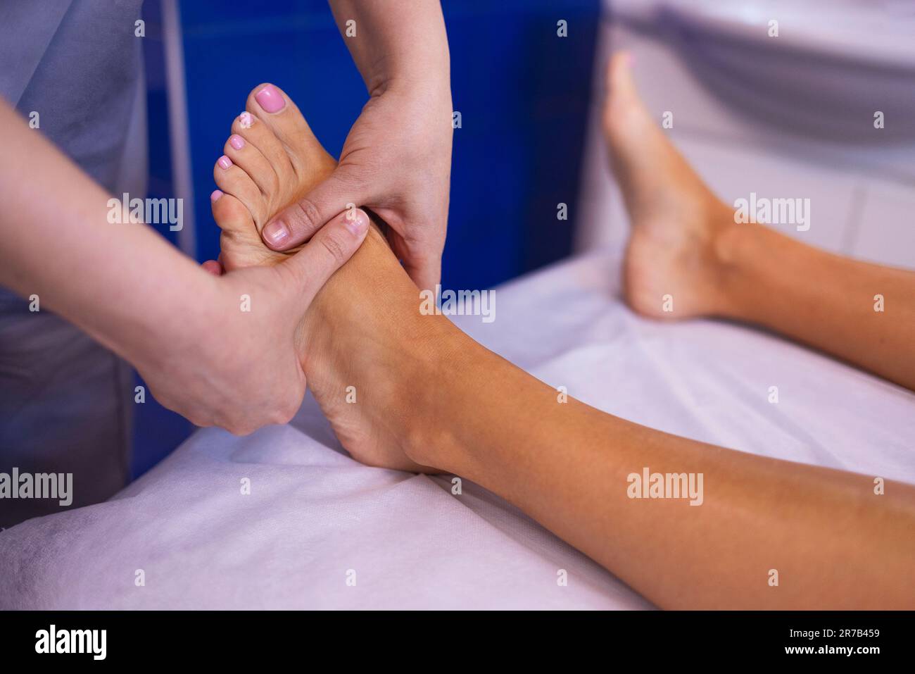 Close up of female foot getting gentle massage. Masseuse holds woman leg in her hands. Young client lies and enjoys relaxing procedure in beauty salon Stock Photo