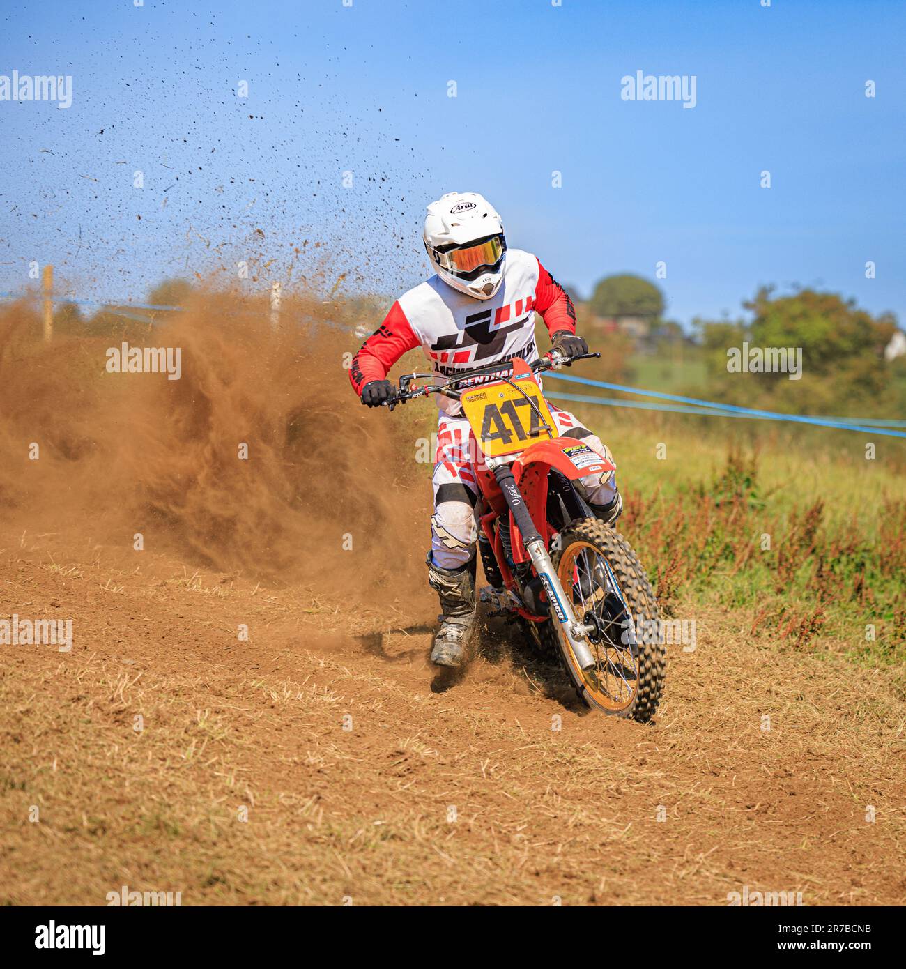 A motocross racer is pictured mid-air, flying sideways while creating a dust wind vortex behind him Stock Photo