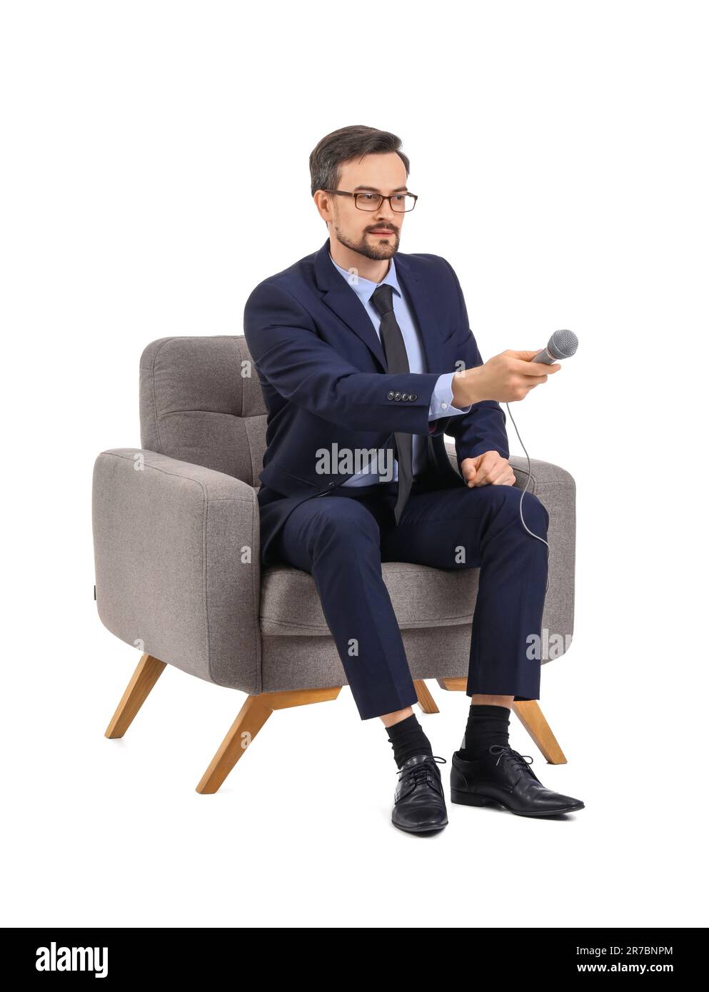 Male journalist with microphone in armchair on white background Stock