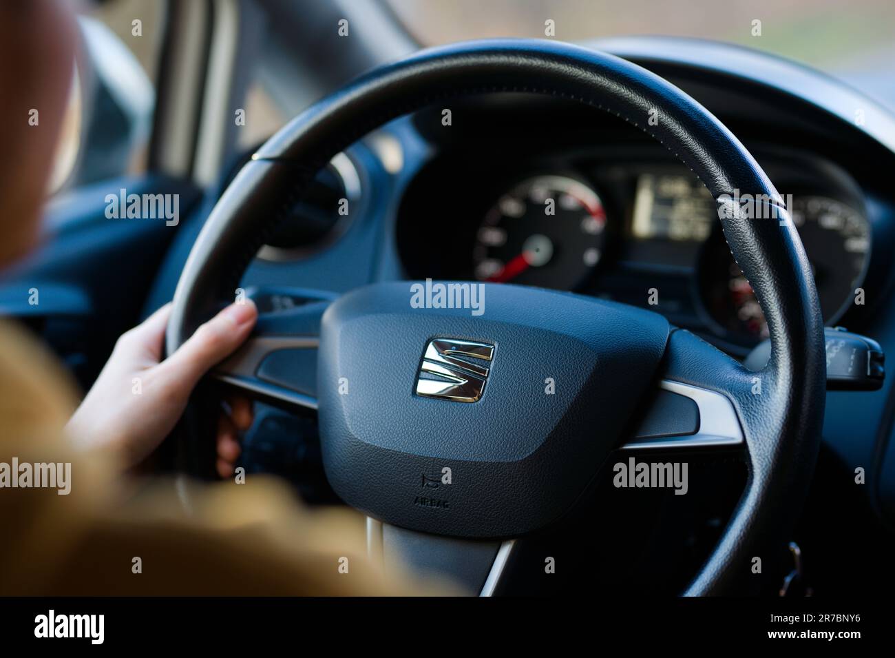 A closeup of a person gripping a steering wheel with their right hand