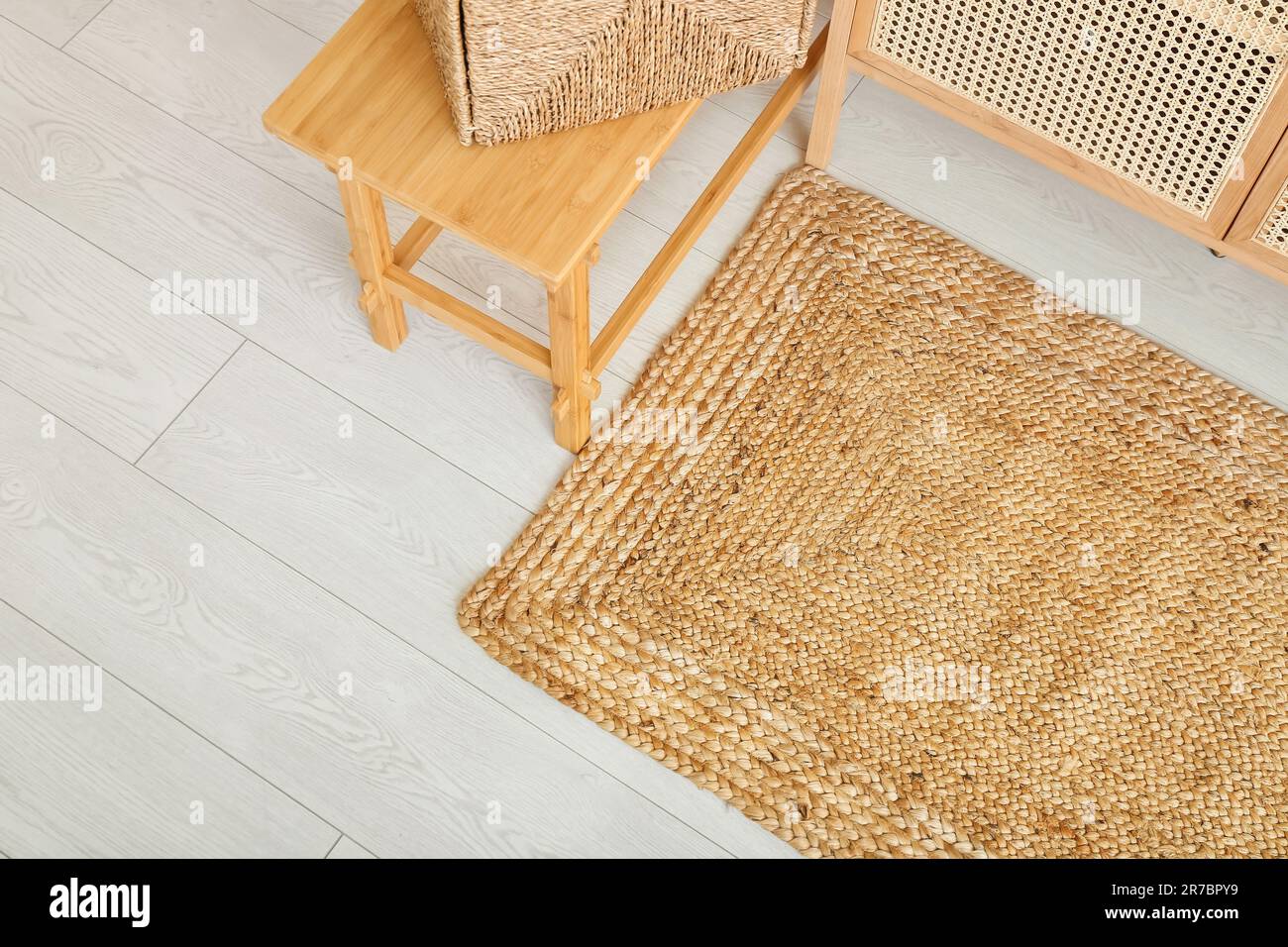 Stylish interior of living room with drawers, chair and wicker rug ...