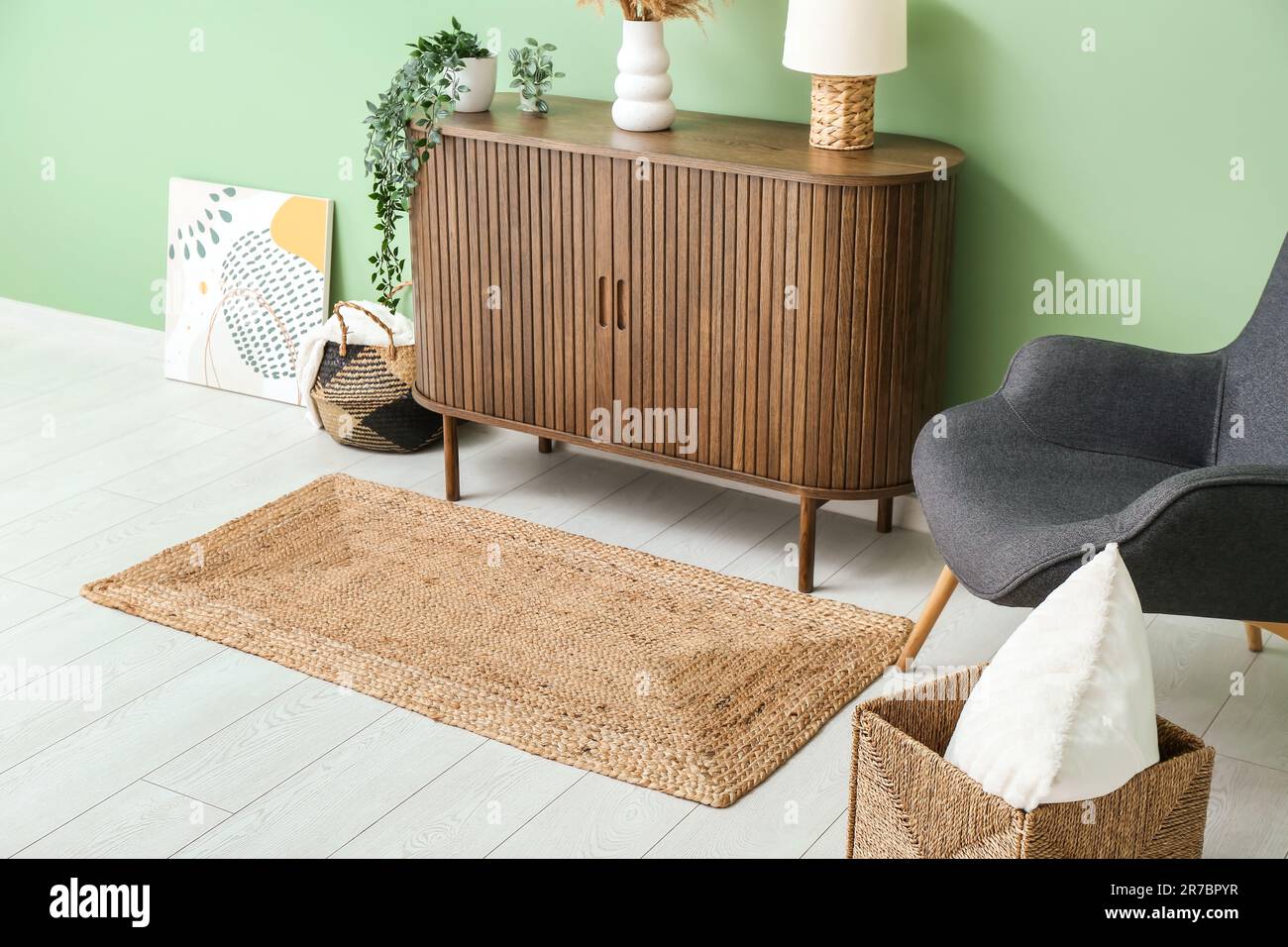 Stylish interior of living room with drawers, armchair and wicker rug ...