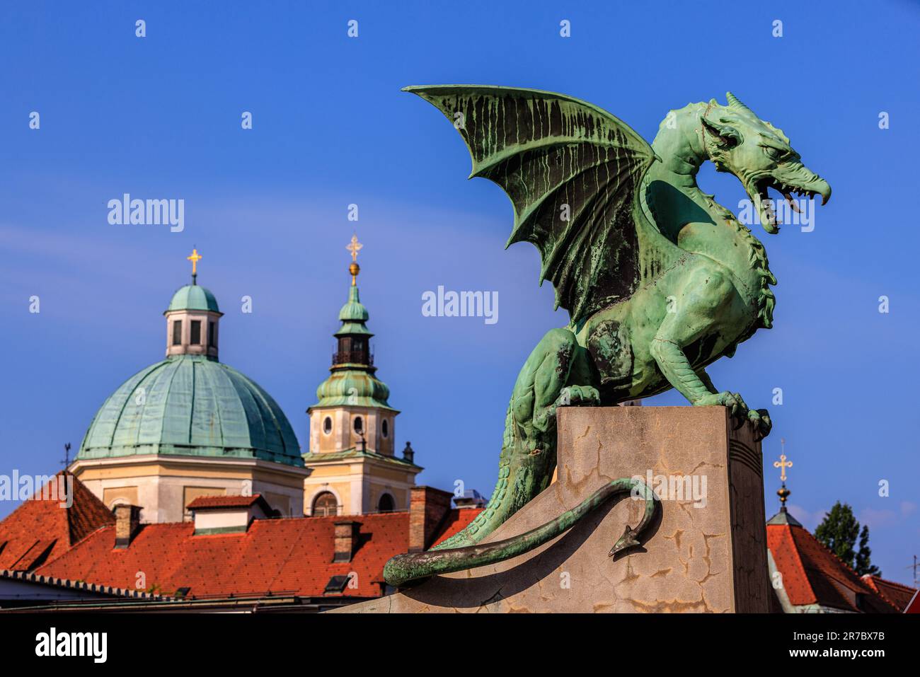 the green statue of the dragon bridge of ljubljana and the green domes of st nicholas cathedral Stock Photo