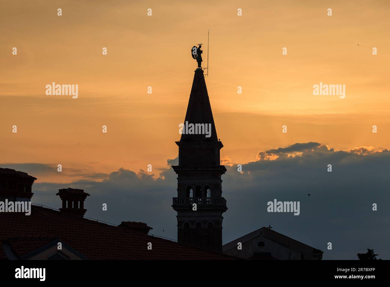 the bell tower of st george's church in piran in silhouette against a ...