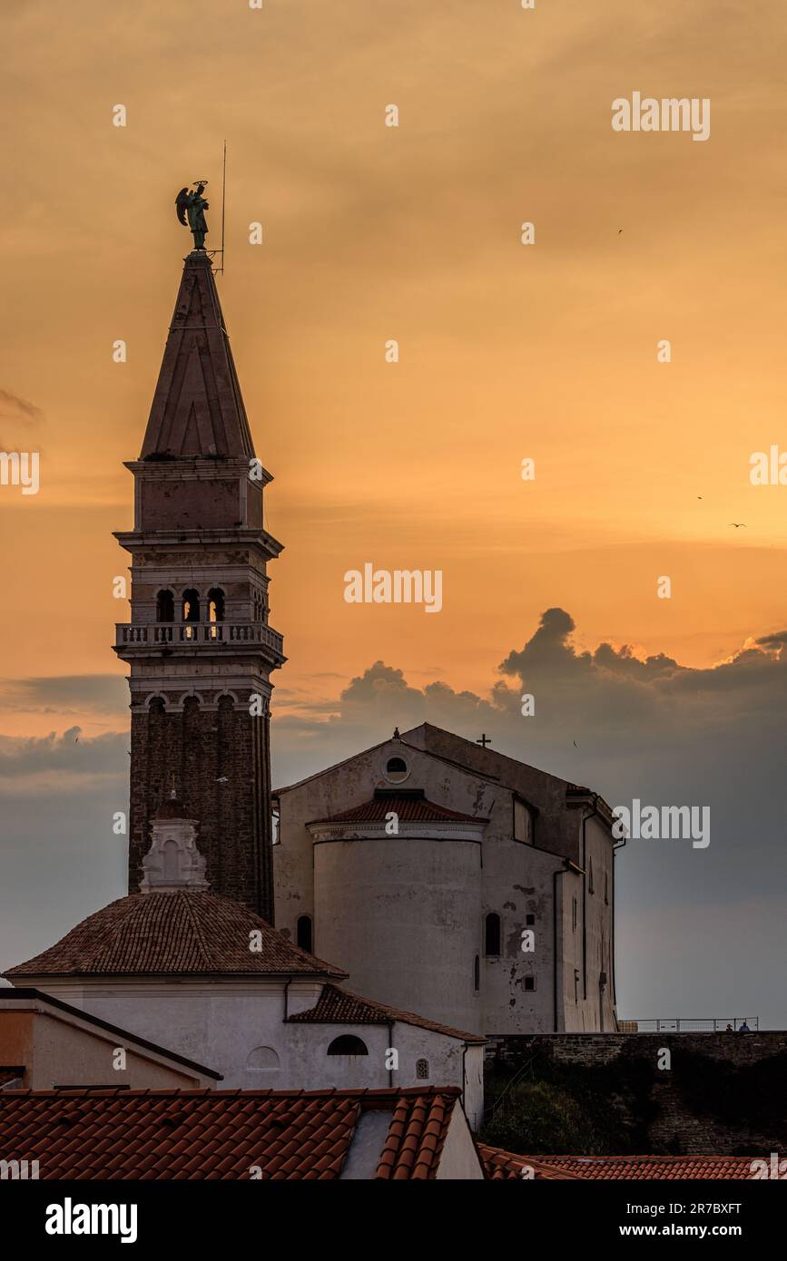the bell tower of st george's church in piran in silhouette against a ...