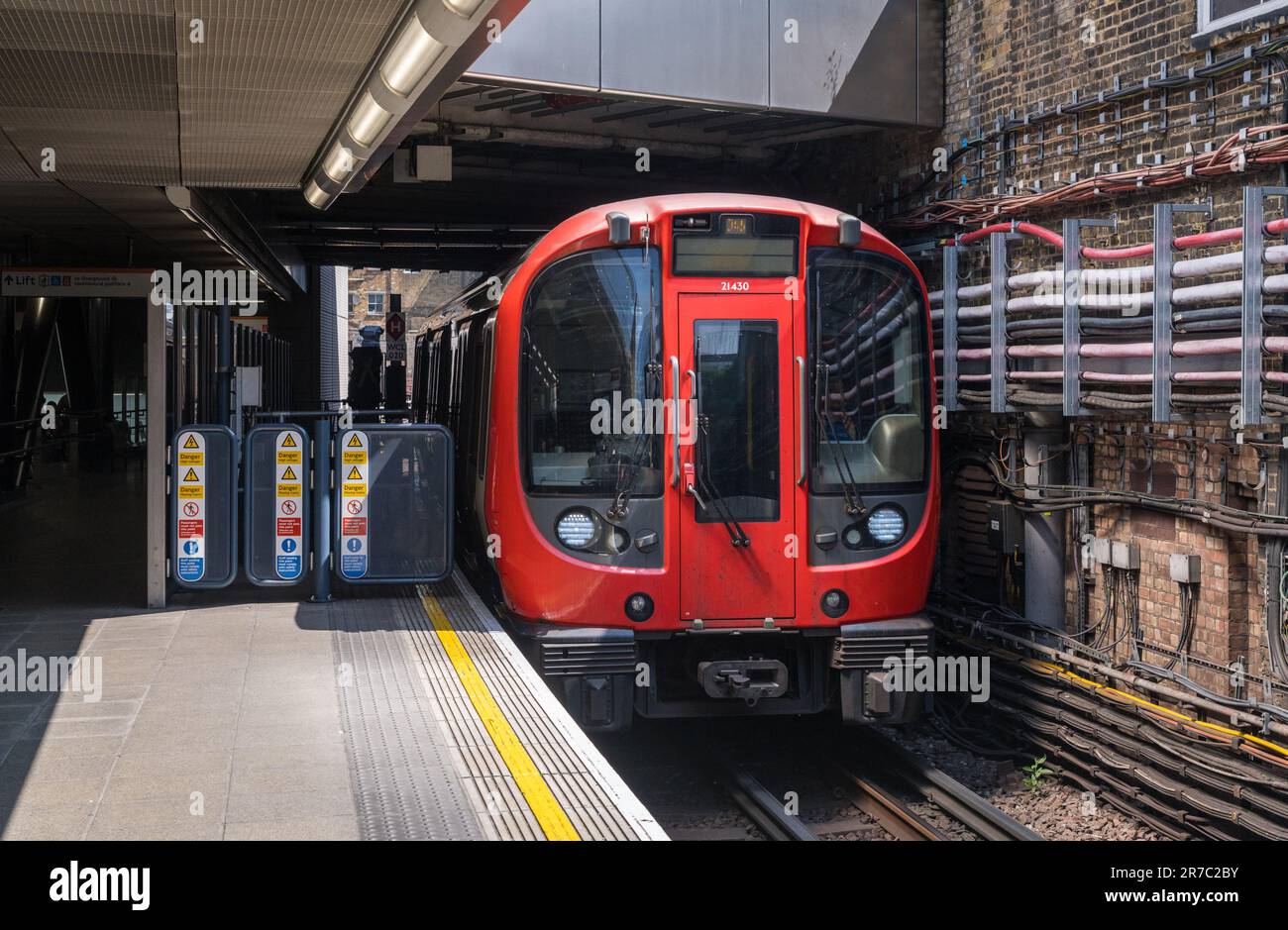 Whitechapel, London - 14 May 2023: London District Line tube train entering the station into sunlight Stock Photo