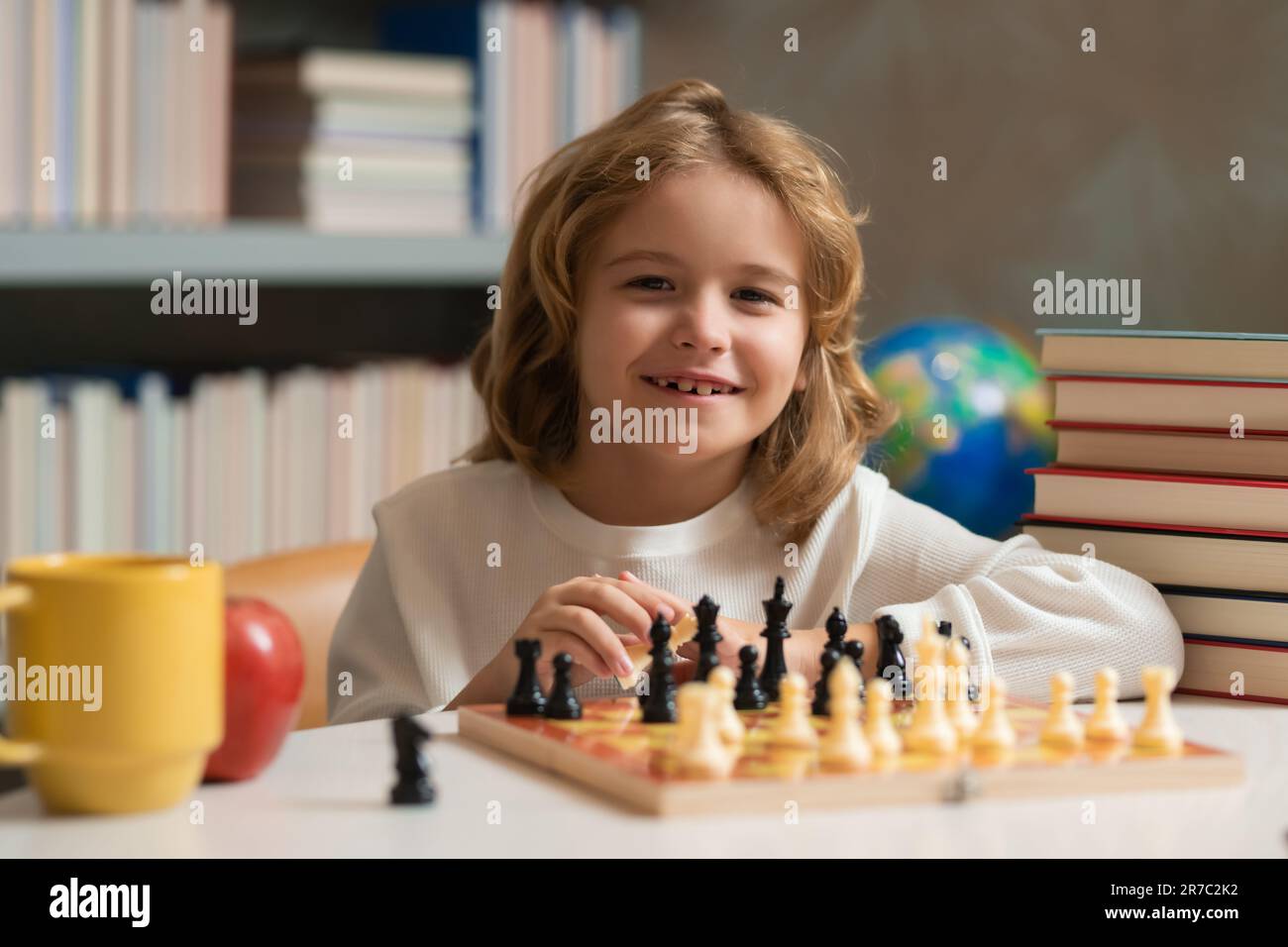 Little kid play chess in school class. Child boy playing board game