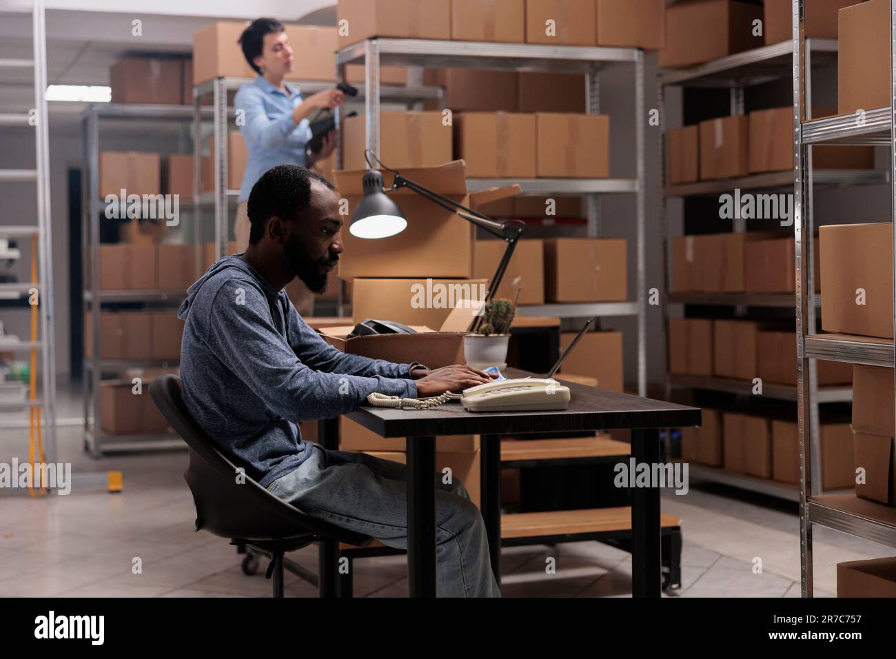 Delivery department manager sitting at desk in warehouse checking