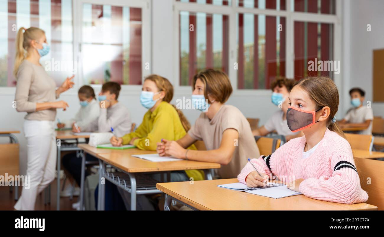 Schoolgirl in mask sitting in classroom Stock Photo - Alamy