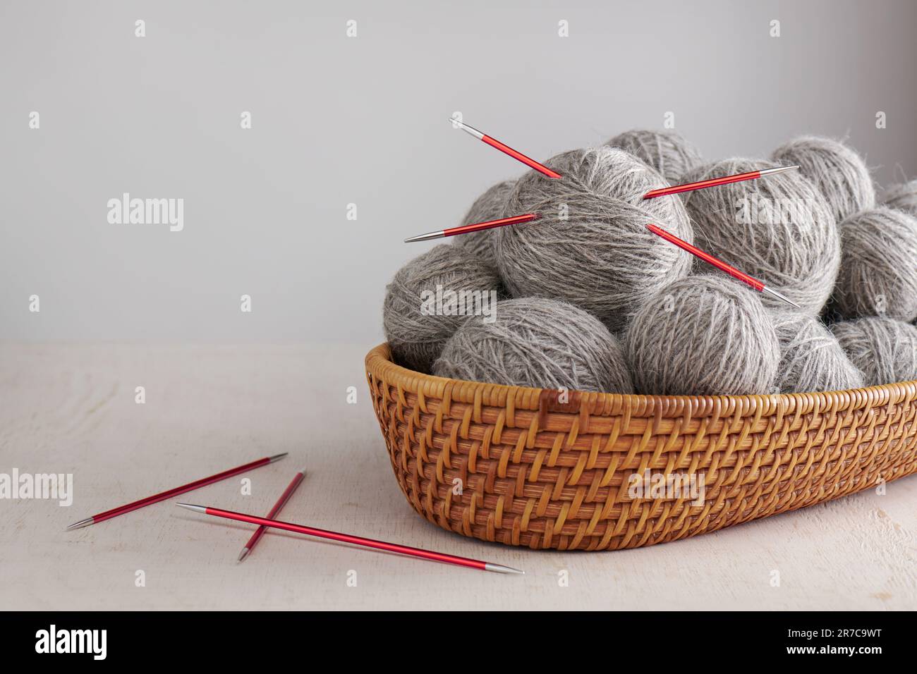 Double pointed knitting needles and balls of yarn in basket Stock Photo