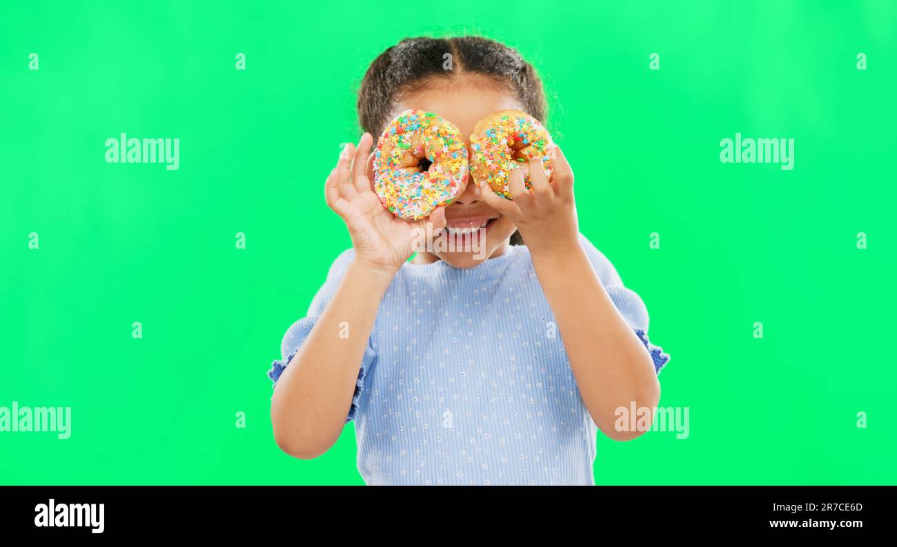 Donut on eyes, smile and child on green background with cake over face