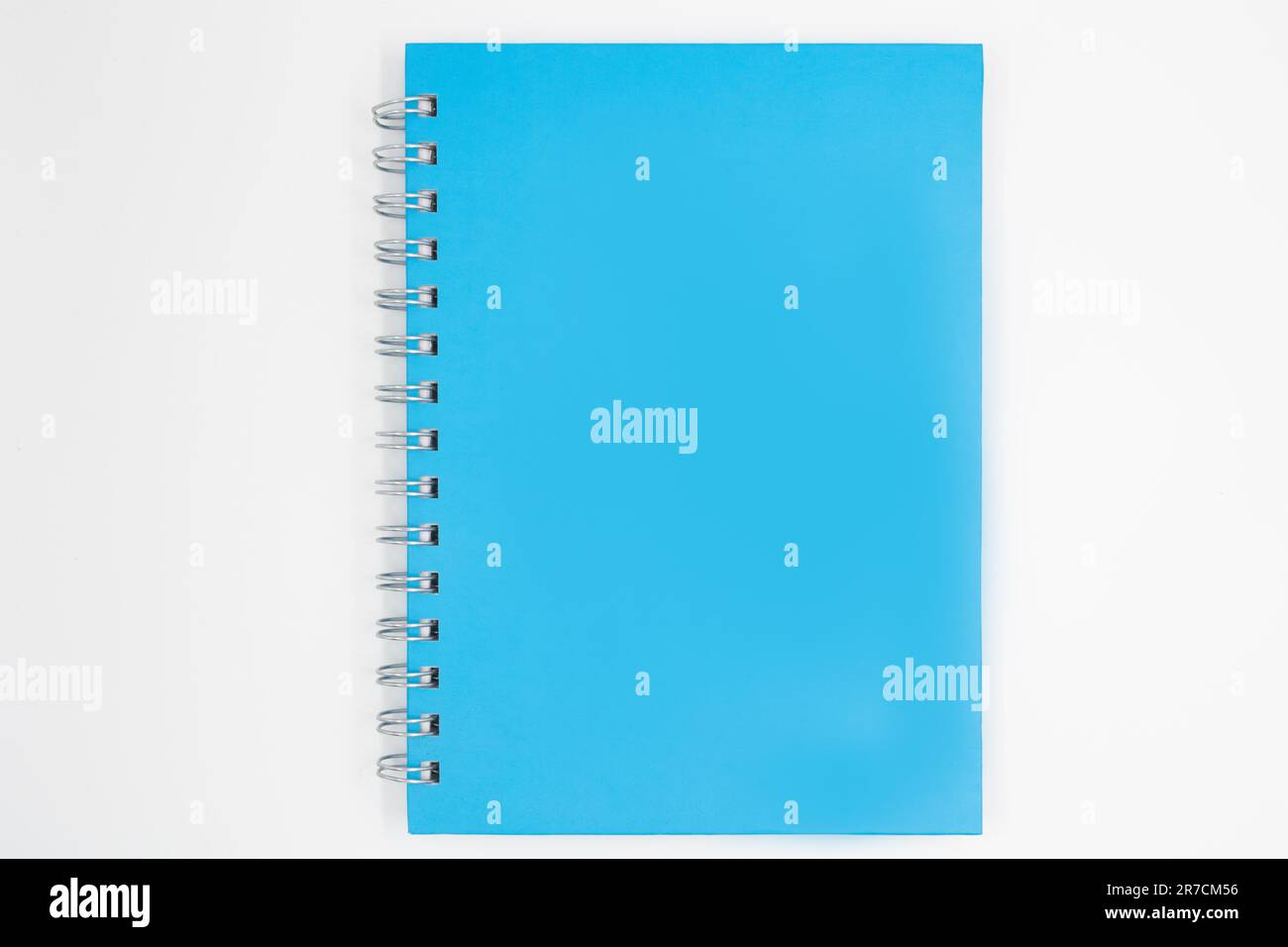 A blue and closed spiral-bound notebook on a white surface, with copy space Stock Photo