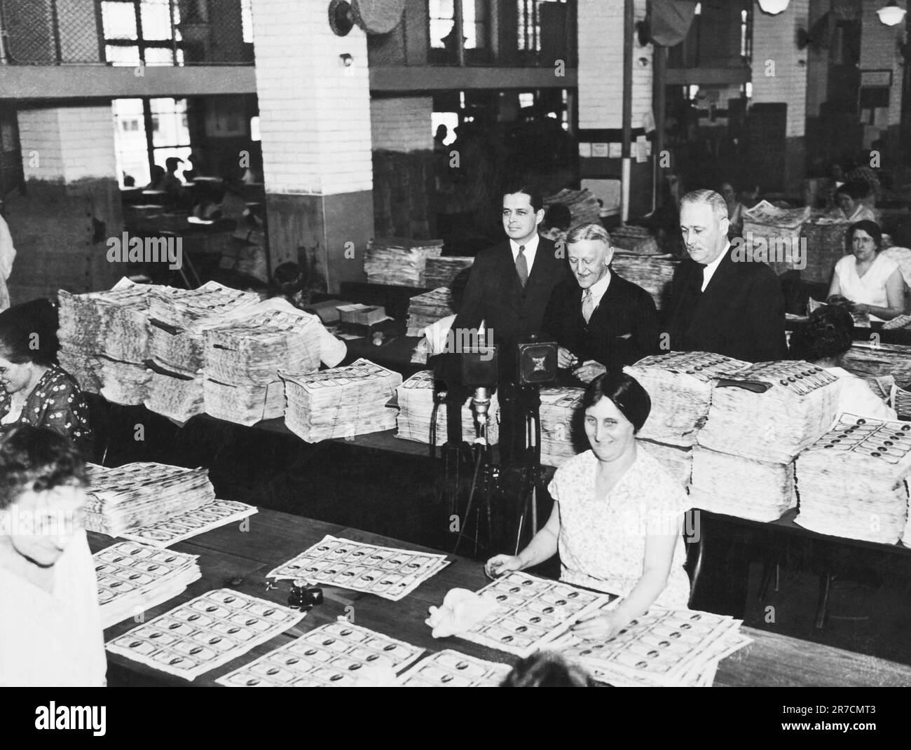 Washington, D.C.:  c. 1929 Workers at the Bureau of Engraving with piles of sheets of dollar bills. Stock Photo
