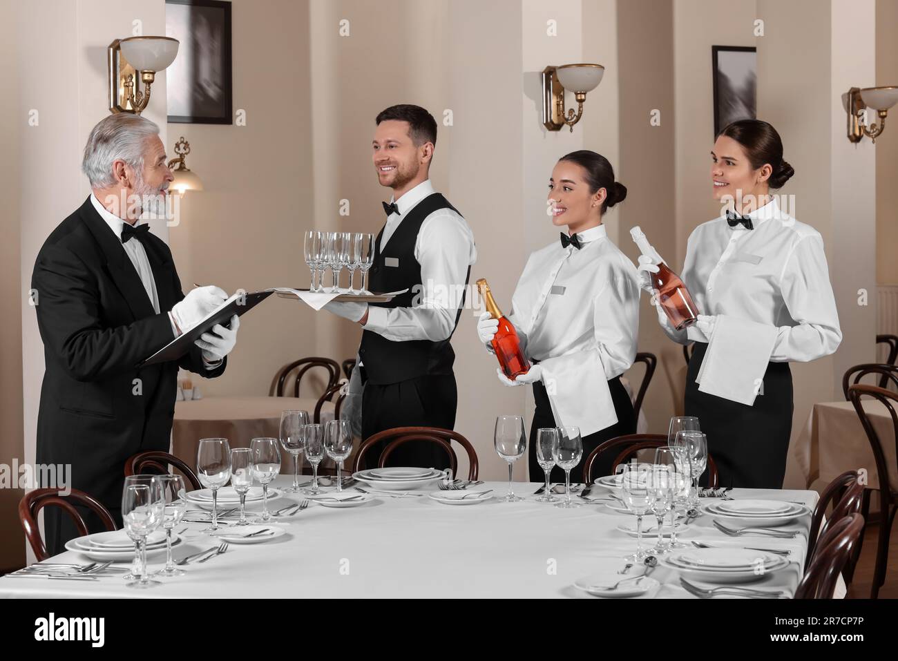 Senior man wearing formal suit teaching trainees in restaurant Senior man wearing formal suit teaching trainees in restaurant