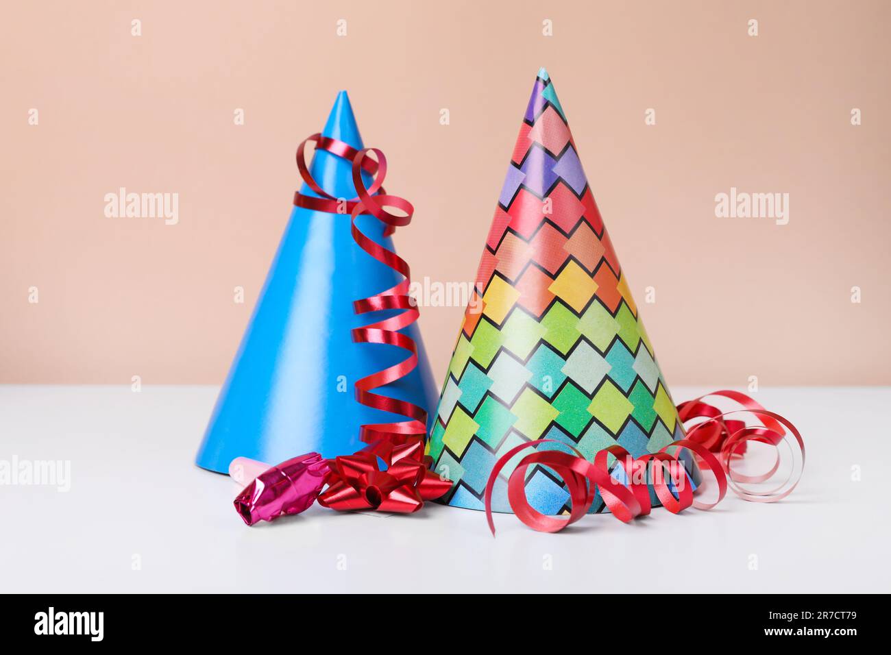 Colorful party hats, streamers and blower on white table. Birthday