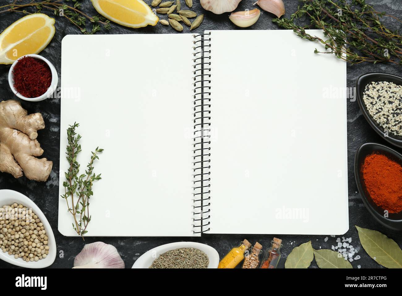 Blank recipe book surrounded by different ingredients on black textured table, flat lay. Space for text Stock Photo