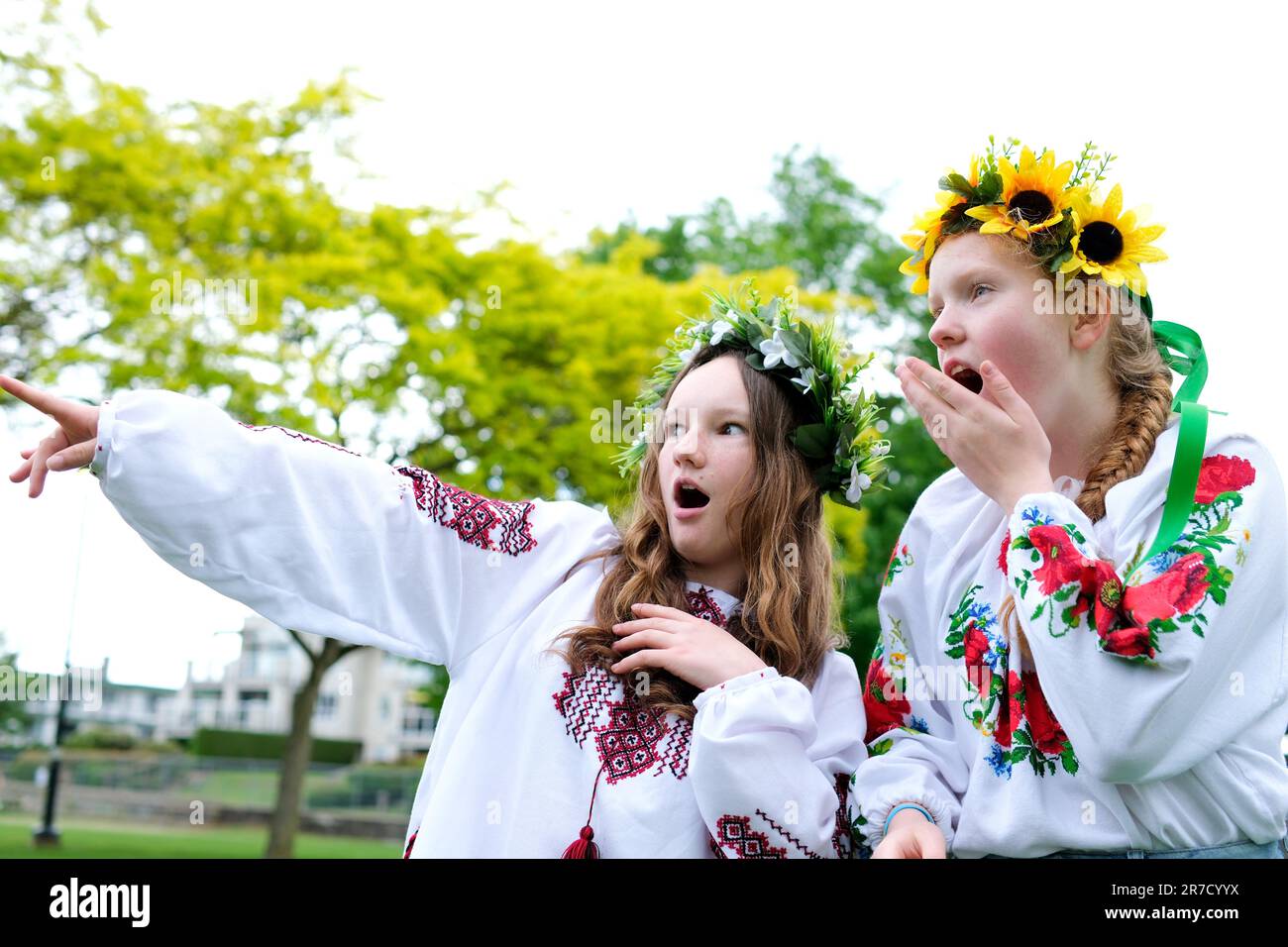 beautiful young women girls weaving wreaths walking laughing chatting in park in garden embroidered national ukrainian shirts wreaths of sunflower flowers and forest white flowers beautiful vyshyvanka Stock Photo