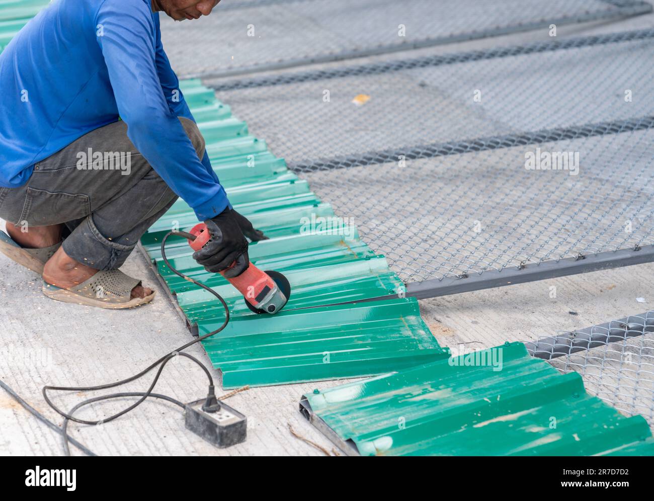 Worker use grinder cutting galvanized metal sheet in building site