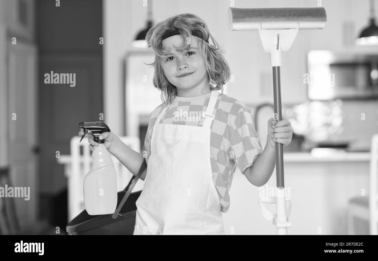 Little kid cleaning at home. Child doing housework having fun. Portrait of child housekeeper with wet flat mop on kitchen interior background. Stock Photo