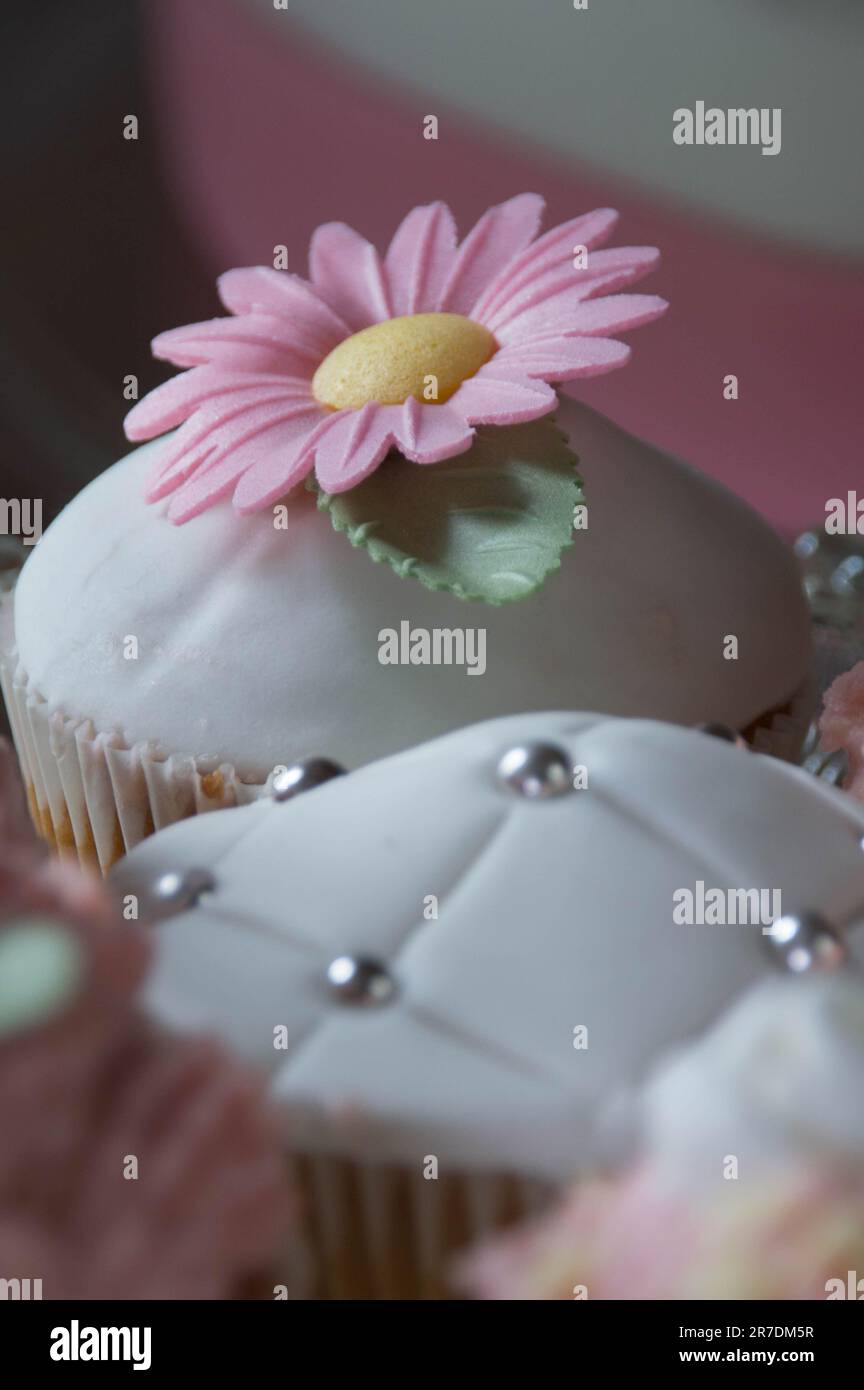 A colorful assortment of cupcakes with white frosting and edible flower
