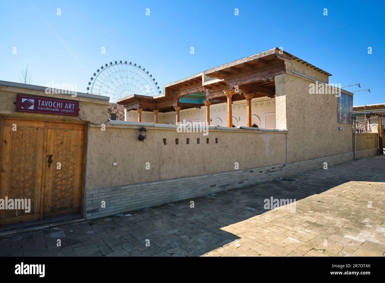 An art gallery in an old courtyard with the ferris wheel in the background. In the recreated, Silk Road era looking village at Anhor park in Tashkent, Stock Photo