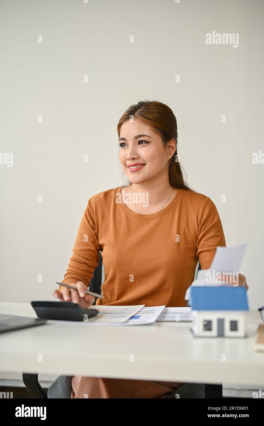 A portrait of an attractive millennial Asian female real estate agent working on a letter of