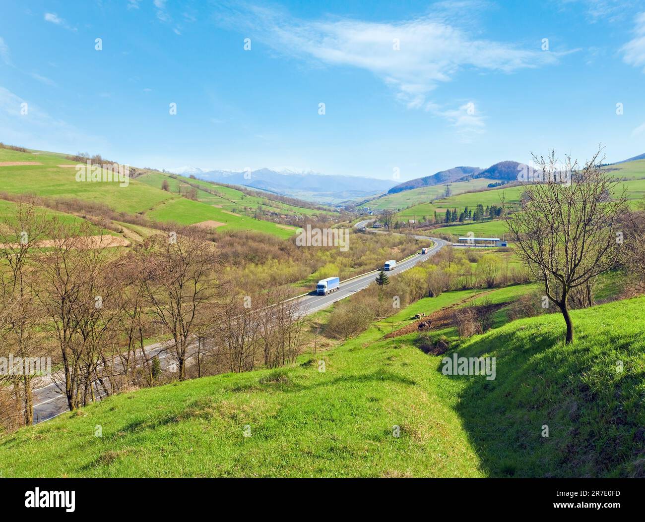 Spring mountain country valley view with farm fields and road Stock