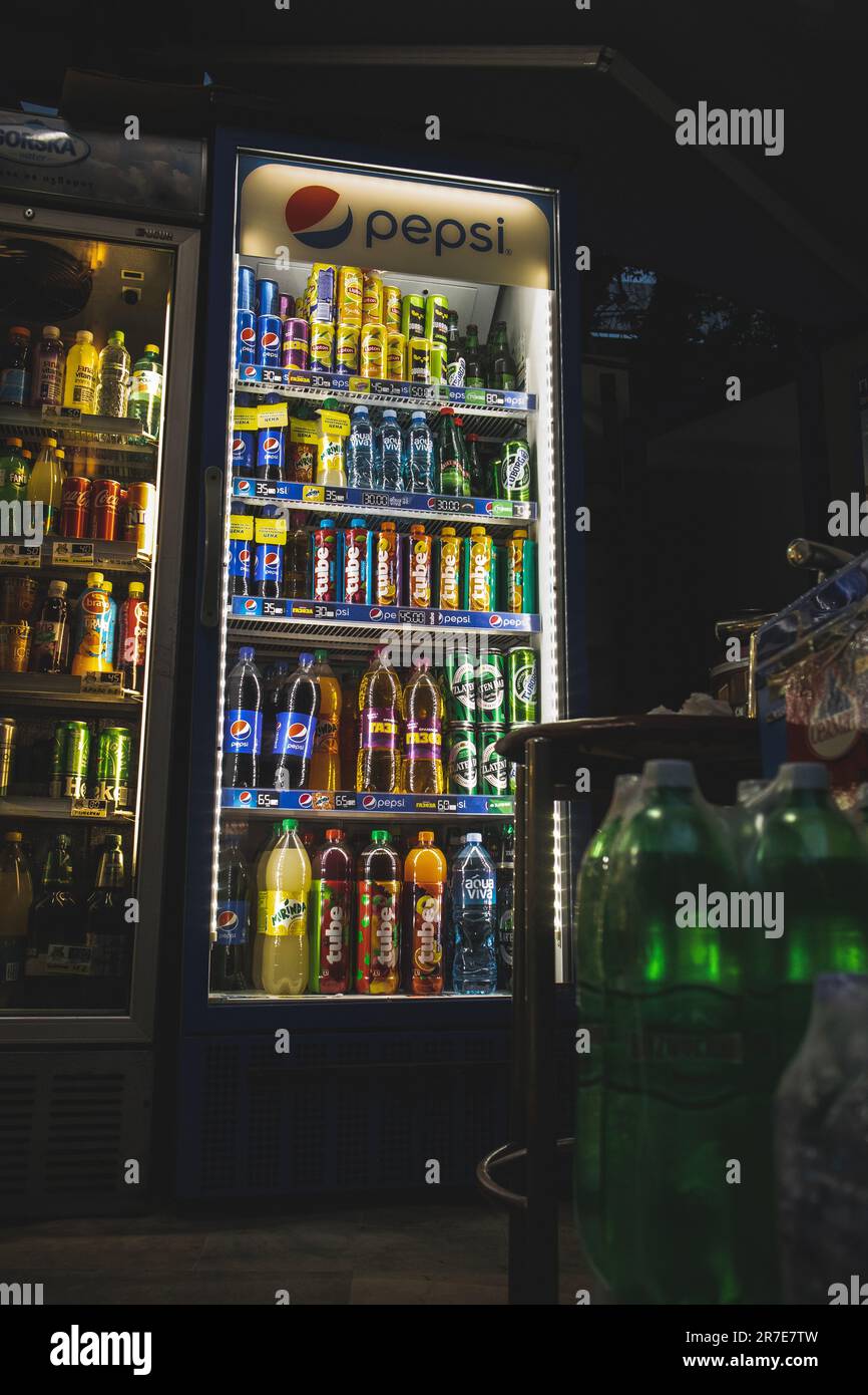 A shop featuring a fridge filled with cold sodas, drinks, bottles, cans and lights on the machine making it cinematic Stock Photo