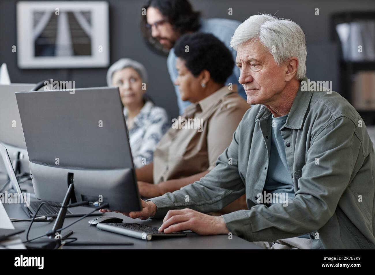 Side view portrait of white haired senior man using computer in tech ...