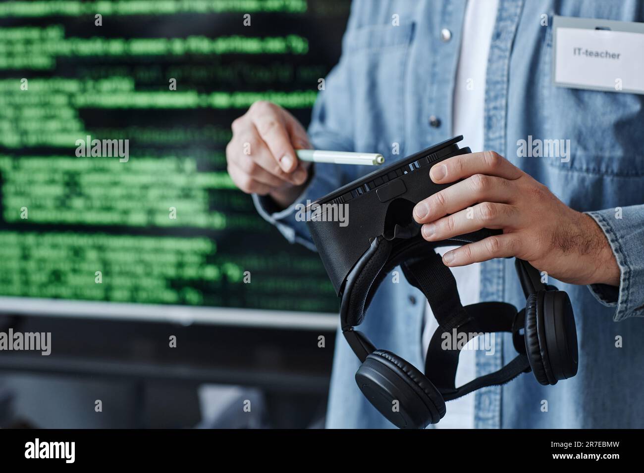Closeup of man holding VR headset against screen with code lines while developing virtual reality software, copy space Stock Photo