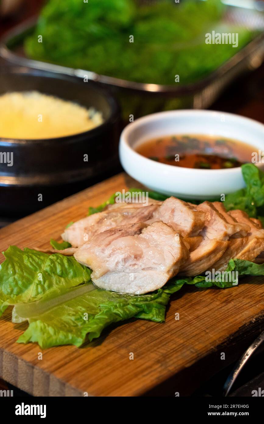 Pan-fried black pork meal in Jeju Korean restaurant, fresh delicious korean food cuisine on iron plate with lettuce, kimchi, banchan and sauce, lifest Stock Photo