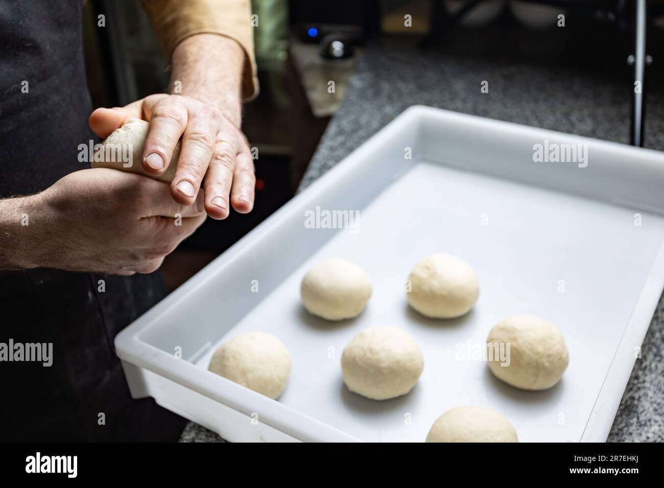 A baker delicately handling dough balls that will be used to bake a pastry Stock Photo
