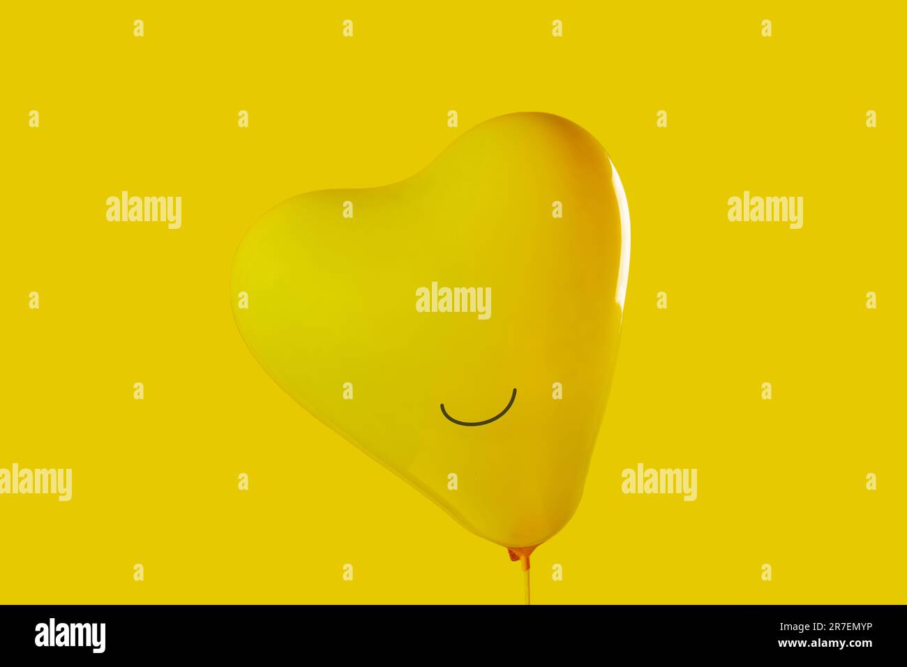 closeup of an inflated yellow heart-shaped balloon with a smile drawn ...
